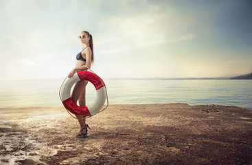 Fashionable woman holding a life buoy at the beach