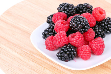 Blackberry and raspberries on white plate