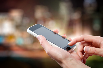 Female hands holding a cell phone (smartphone) with tuchscreen in night