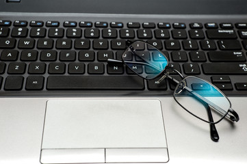 Close up pair of glasses on the laptop keyboard