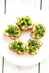 Tasty fresh bruschetta on plate on white wooden background