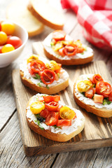 Tasty fresh bruschetta with tomatoes on cutting board on grey wo