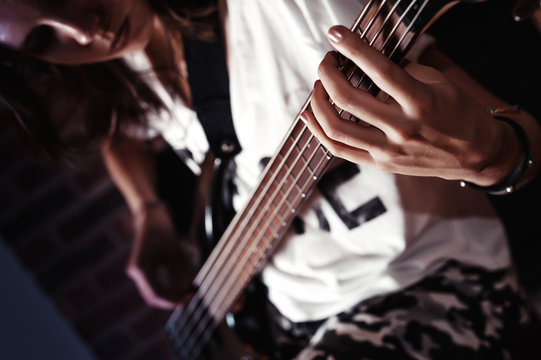 Young adult girl playing five string bass guitar. Color image
