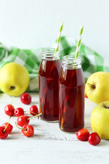 Glass of cherry juice with apple on white wooden background