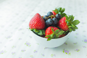 Close up of a small bowl containing berries strawberries and blueberries