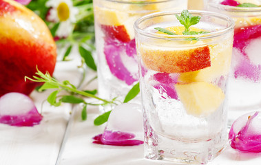 Fresh sparkling beverage with peaches and ice with rose petals o
