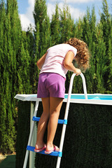 Blonde girl climb on the ladder of the detachable pool in the country house