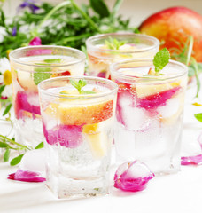 Fresh sparkling beverage with peaches and ice with rose petals o