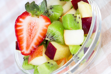 Fruit salad in white plate on tablecloth