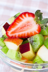 Fruit salad in white plate on tablecloth