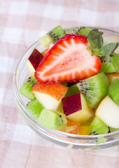 Fruit salad in white plate on tablecloth