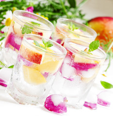 Fresh sparkling beverage with peaches and ice with rose petals o