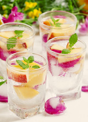 Fresh sparkling beverage with peaches and ice with rose petals o
