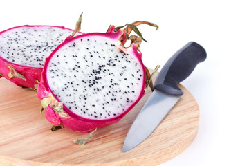 Dragon fruit and knife on wooden cutting board