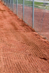 Raked warning track near the chain link fence at a softball field in New Mexico