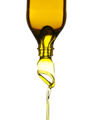 Olive oil pouring from glass bottle against white background