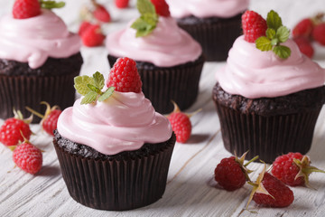 Chocolate cupcakes with cream and fresh raspberries closeup. horizontal
