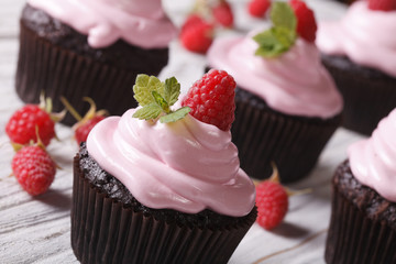Chocolate cupcakes with pink cream and raspberry close-up. 
