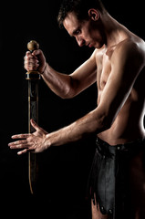 Ancient  muscular warrior gladiator with sword on black background