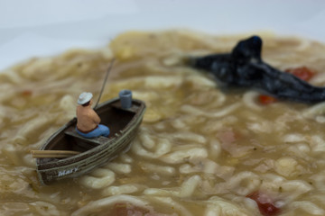 Miniature man fishing in soup