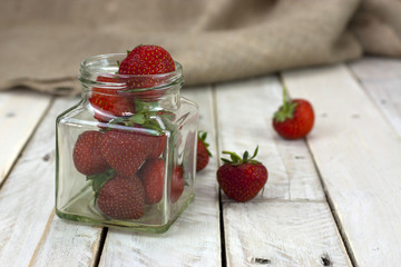 Stawberries in a jar and spilt on table