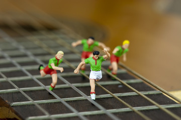 Men running down the arm of a guitar