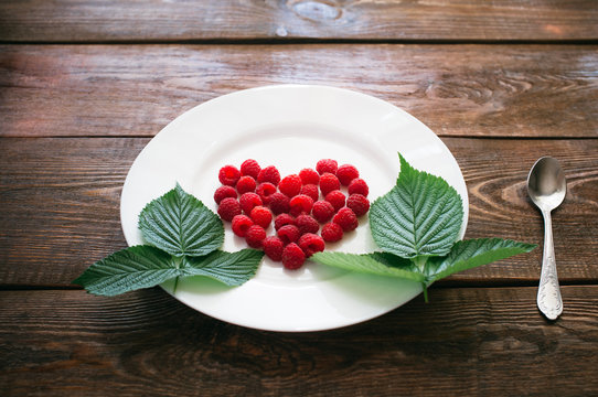 Heart from raspberry on a white plate