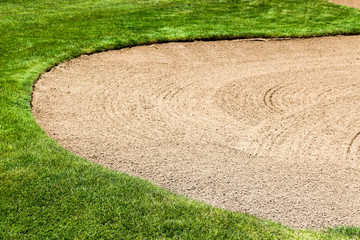 Curving raked sand in a sand trap at a golf course with copy space