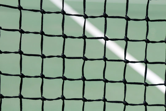 Full frame close up image of a tennis court net with green court and white line 