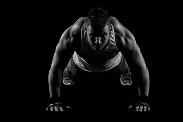 Bodybuilder posing on black background.