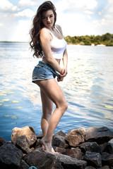 The young, sexy girl in a dress on the river bank, rocks