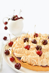 Homemade meringue cake with cherry on white table cloth