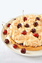 Homemade meringue cake with cherry on white table cloth
