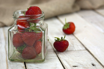 Stawberries in a jar and spilt on table