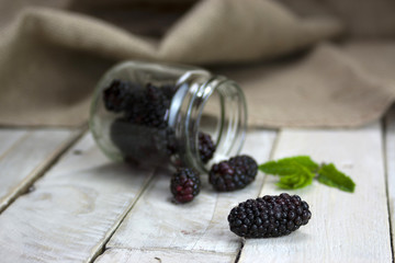 Fototapeta na wymiar Blackberries in a jar and spilt on table