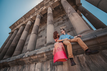 Fototapeta premium Young couple sitting near the ancient temple of Garni in Armenia