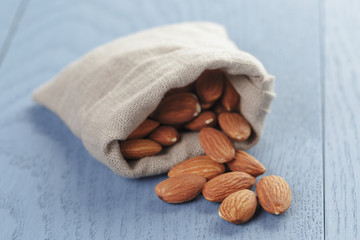 almonds in sack bag on blue wood table