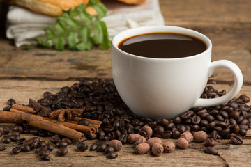Coffee cup and coffee bean on a wooden table. Dark background.