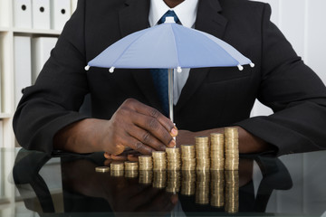 Businessman Protecting Coins With Umbrella - Powered by Adobe