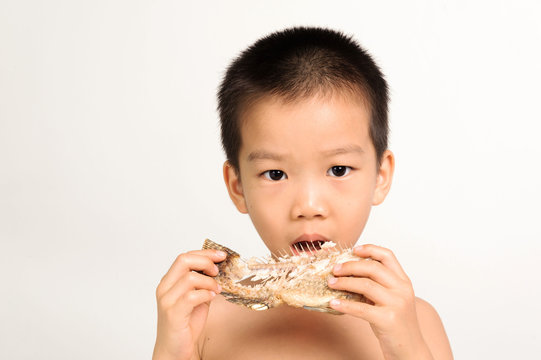 Young Asian Boy Eating Fish