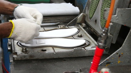 worker making shoe sole by mold pressing machine in Asia footwear factory