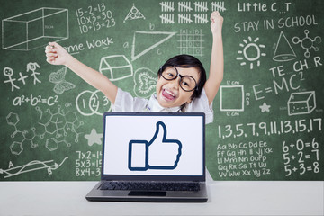 Satisfied child raise hands with an OK sign on laptop