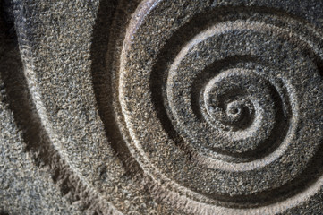 Close-up of spiral pattern carved in rough stone in an ancient Hindu shrine in India