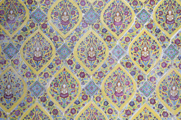 Intricate decorative Buddhist background featuring images of the Buddha amongst colourful flower patterns at a temple in Bangkok, Thailand