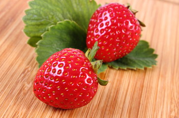 Strawberry with leaves on wooden surface