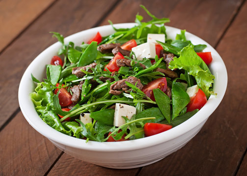 Salad with veal slices, arugula, tomatoes and feta cheese
