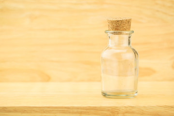 Glass bottle with cork on wood table and blur wooden wall, Copy