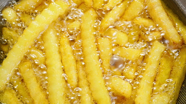 Tasty French-fries cooking in boiling oil. 