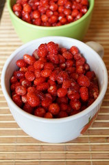 Red fresh wild strawberry in a big white mug stand on a table