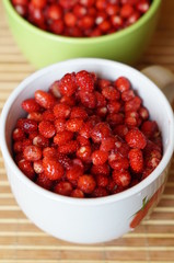 Red fresh wild strawberry in a big white mug stand on a table
